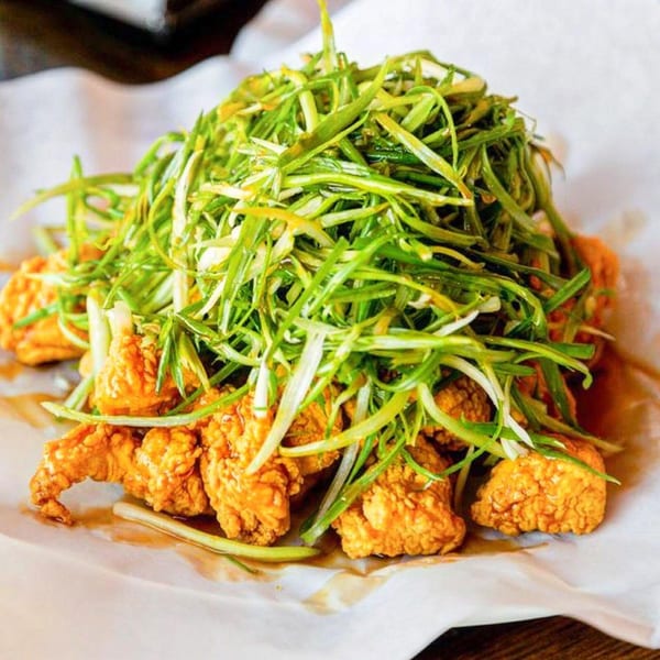 Angry Chicken's fried chicken pieces topped with a generous pile of fresh green onions.