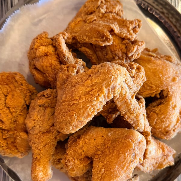 Close-up of a platter filled with golden-brown, crispy fried chicken pieces from Angry Chicken.