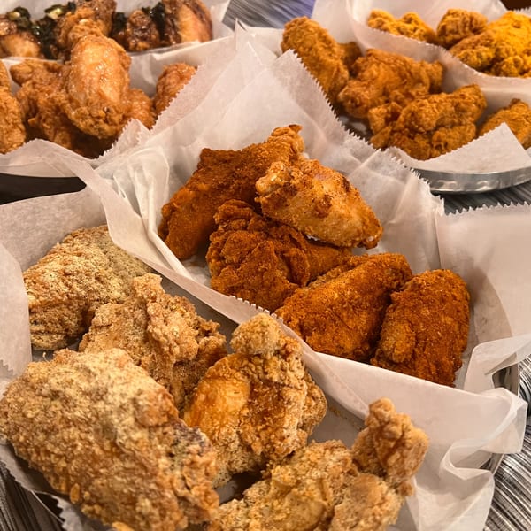 Assortment of Angry Chicken's fried chicken wings in various flavors, served in paper-lined baskets.