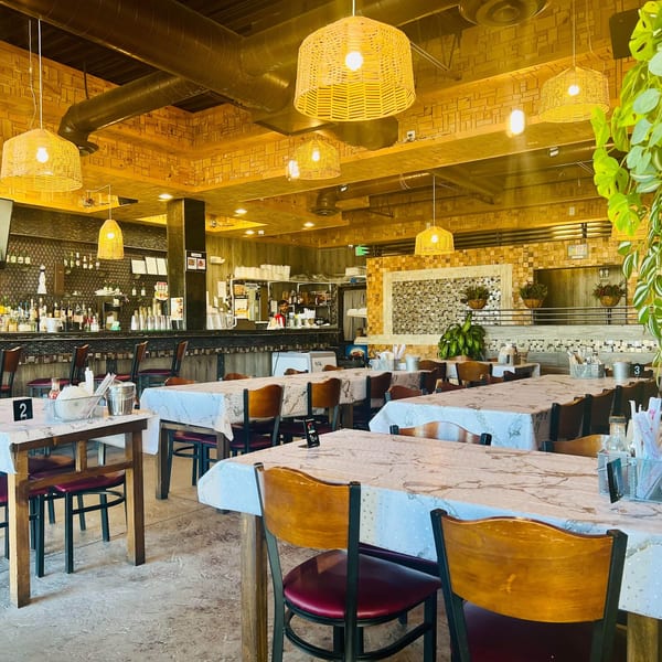 Interior of Angry Chicken restaurant with empty tables, chairs, and a bar area in the background.